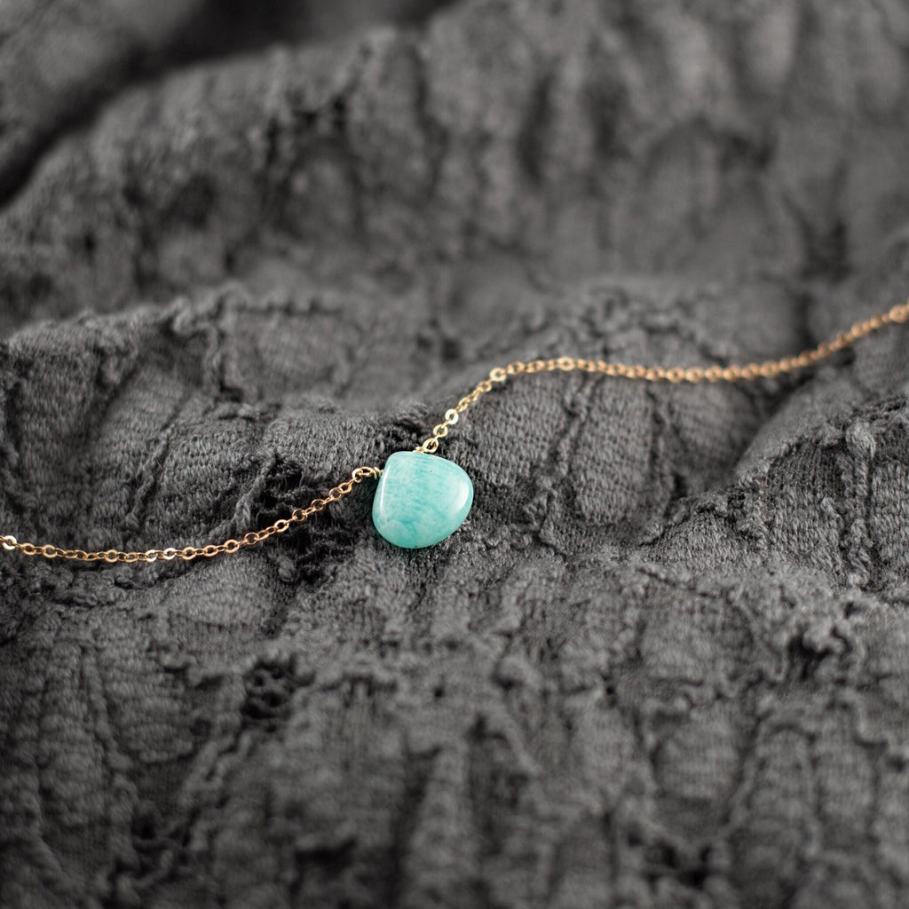 a gold chain with a turquoise stone on it