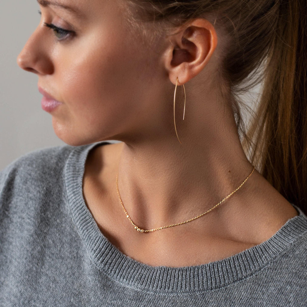 a woman wearing a pair of gold earrings