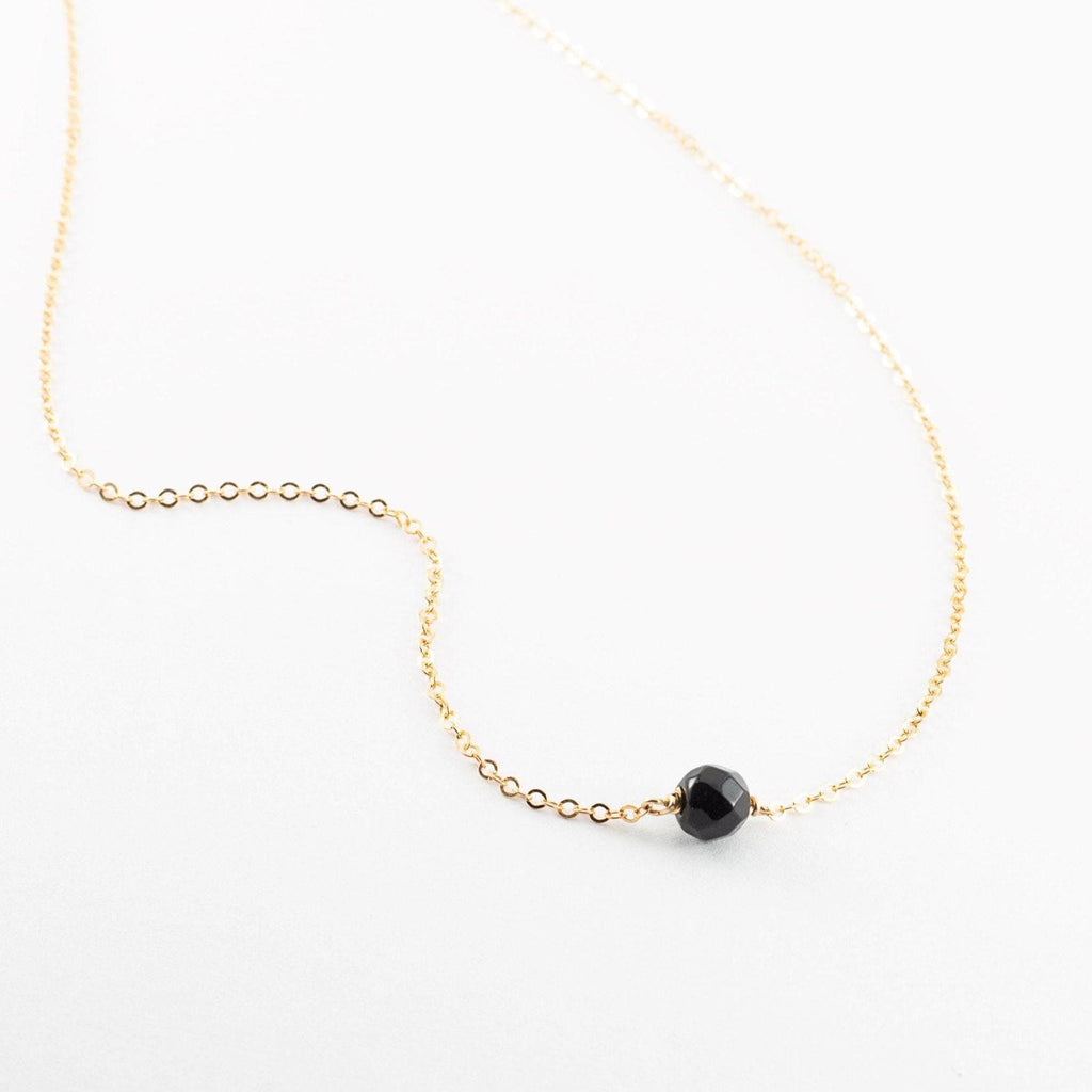 a gold chain with a black bead on it